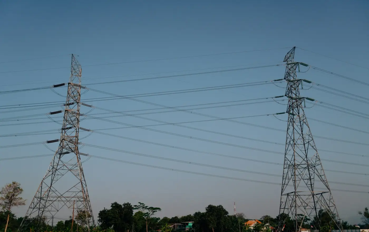 Two transmission towers with small boxes around each insulator